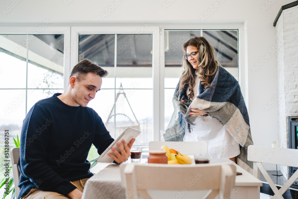 Couple female and male caucasian sitting in a living room drinking coffee and looking at their tablet shopping online Technology and modern lifestyle concept Couple female and male caucasian sitting in a living room drinking coffee and looking at their tablet shopping online Technology and modern lifestyle concept