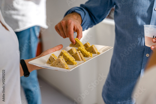 Un homme se sert une mignardise sur une assiette amenée par une serveuse photo