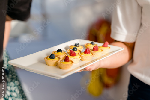 Une serveuse avec un plateau de petits g  teaux aux fruits