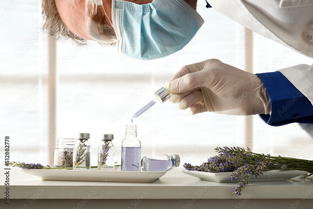 Scientist developing a product with lavender essence in glass vials Scientist developing a product with lavender essence in glass vials