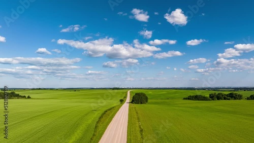 hyperlapse flight over the hills and gravel road on a summer day with a blue sky and fluffy clouds