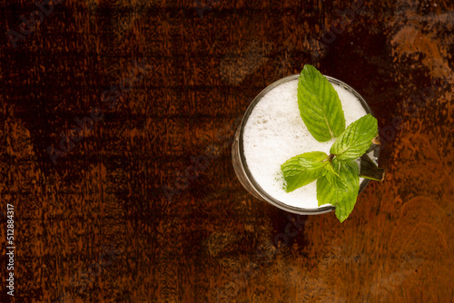 refreshing long juice with mojito foam, mint on wooden table top view photo