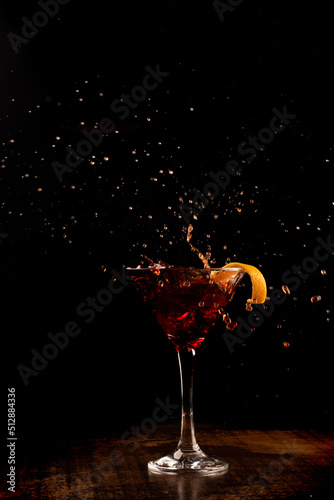 Canvastavla Splash shot with orange martini cocktail drink on wooden counter with dark backg