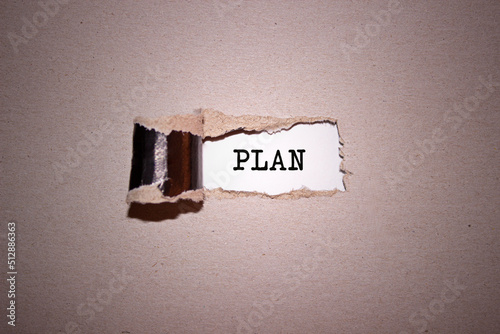 The text Plan appearing behind torn brown paper.