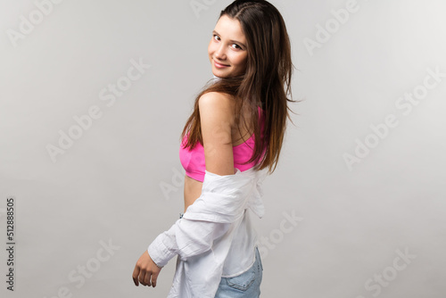 Side view photo of a happy smiling pretty young lady wearing modern teenage clothes posing for the camera with naked shoulder.