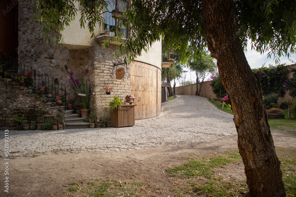 alley street with a graden and a tree at one side and an old house in a  medieval italian tuscany villa in Val'Quirico, Tlaxcala, Puebla, Mexico  foto de Stock | Adobe Stock