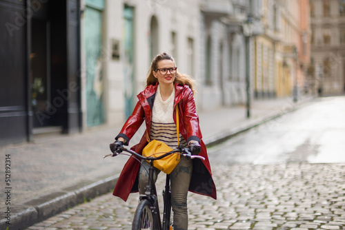 stylish woman outside on city street riding bicycle