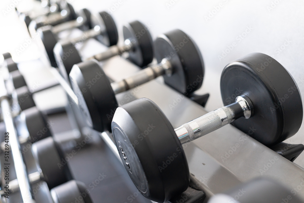 Stand with dumbbells. Sports and fitness room. Weight Training Equipment. Black dumbbell set, many dumbbells on rack in sport fitness center