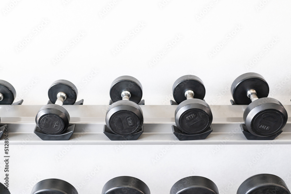 Stand with dumbbells. Sports and fitness room. Weight Training Equipment. Black dumbbell set, many dumbbells on rack in sport fitness center Stand with dumbbells. Sports and fitness room. Weight Training Equipment. Black dumbbell set, many dumbbells on rack in sport fitness center