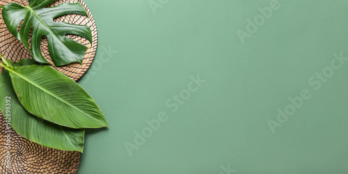 фотографія Tropical leaves and wicker mats on green background with space for text