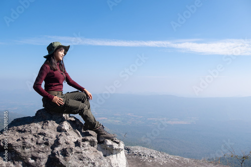 A traveler sits on a rock on a high mountain with a beautiful view of the sky. photo