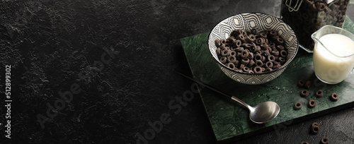 Composition with tasty cereal rings and milk on dark background with space for text