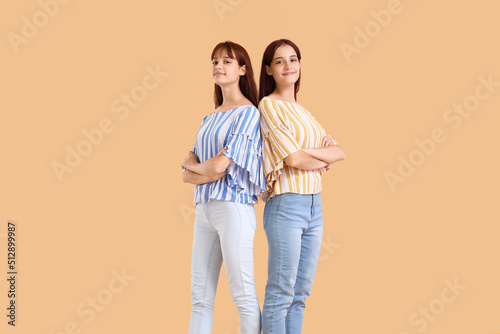 Teenage twin sisters on beige background