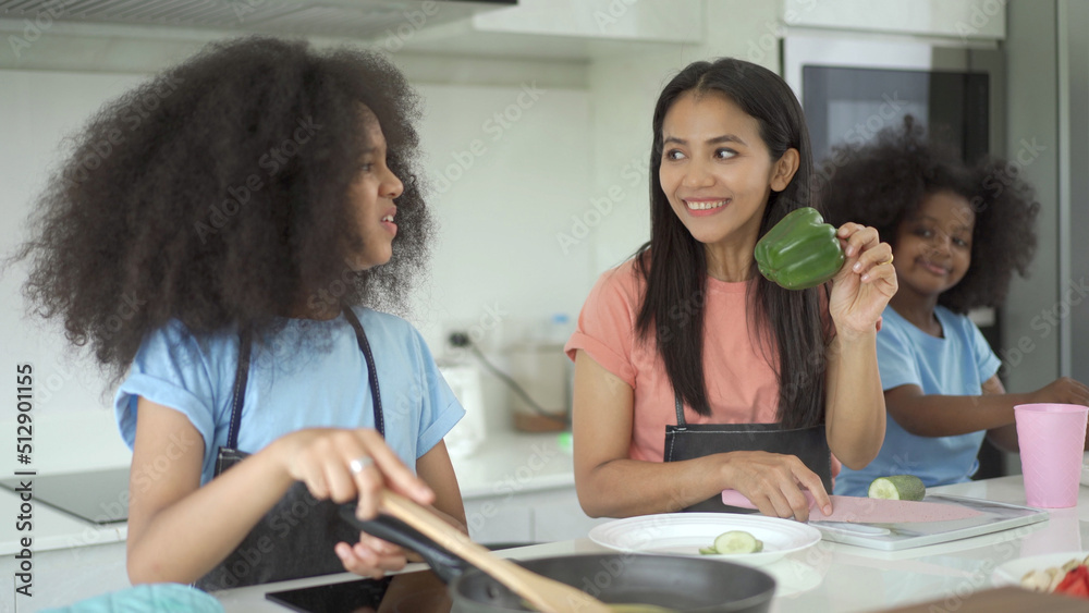 Happy family cooking together, mother let her daughters cook in a kitchen. Happy family cooking together, mother let her daughters cook in a kitchen.