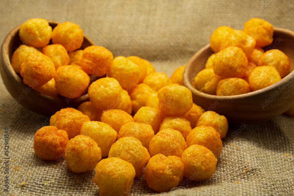 Cheese flavoured Puffs or balls closeup over gunny sack background Cheese flavoured Puffs or balls closeup over gunny sack background