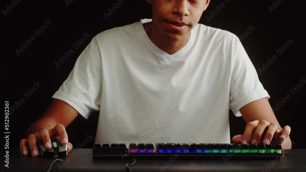 African American man gamer using backlight keyboard close-up, guy playing video game. Male hands pushing buttons on computer mouse. Programmer or hacker working in networks, cyberspace. African American man gamer using backlight keyboard close-up, guy playing video game. Male hands pushing buttons on computer mouse. Programmer or hacker working in networks, cyberspace.