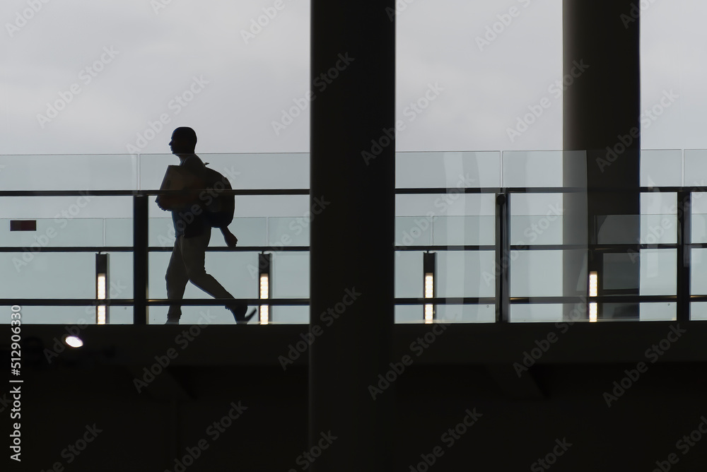Silhouette of people with luggage walking in an airport, with copy space.