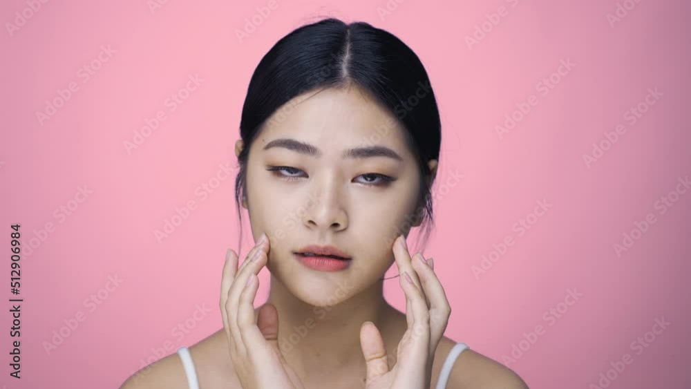 Close up Beauty shot of Beautiful Asian girl looking at camera isolated on pink background Close up Beauty shot of Beautiful Asian girl looking at camera isolated on pink background