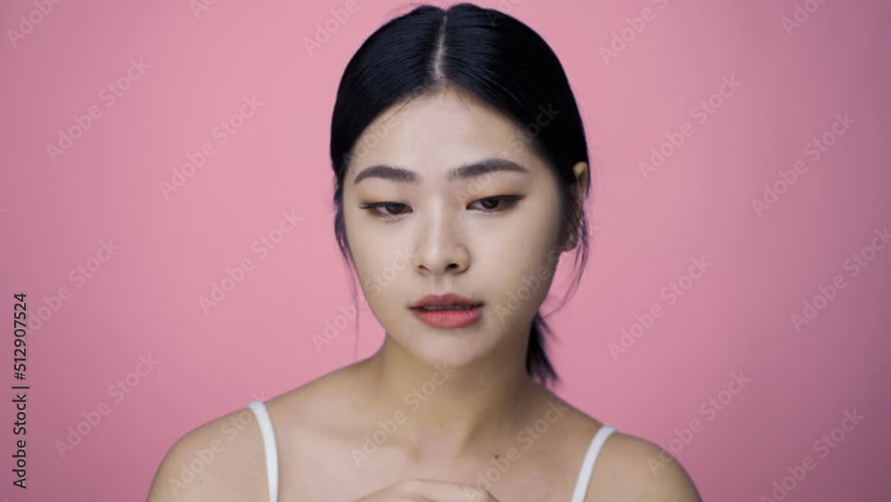 Close up Beauty shot of Beautiful Asian girl looking at camera isolated on pink background Close up Beauty shot of Beautiful Asian girl looking at camera isolated on pink background
