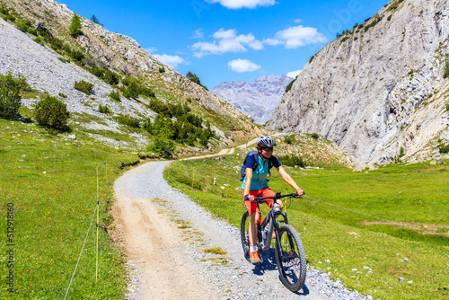 Woman tourist cycling on mtb bike in beautiful Alpisella valley on sunny summer day, Alps Mountains, Italy