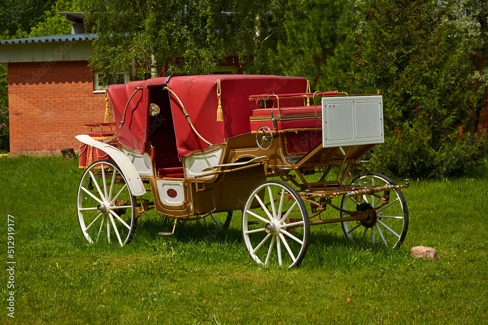 A vintage carriage is standing on the lawn. Without horses