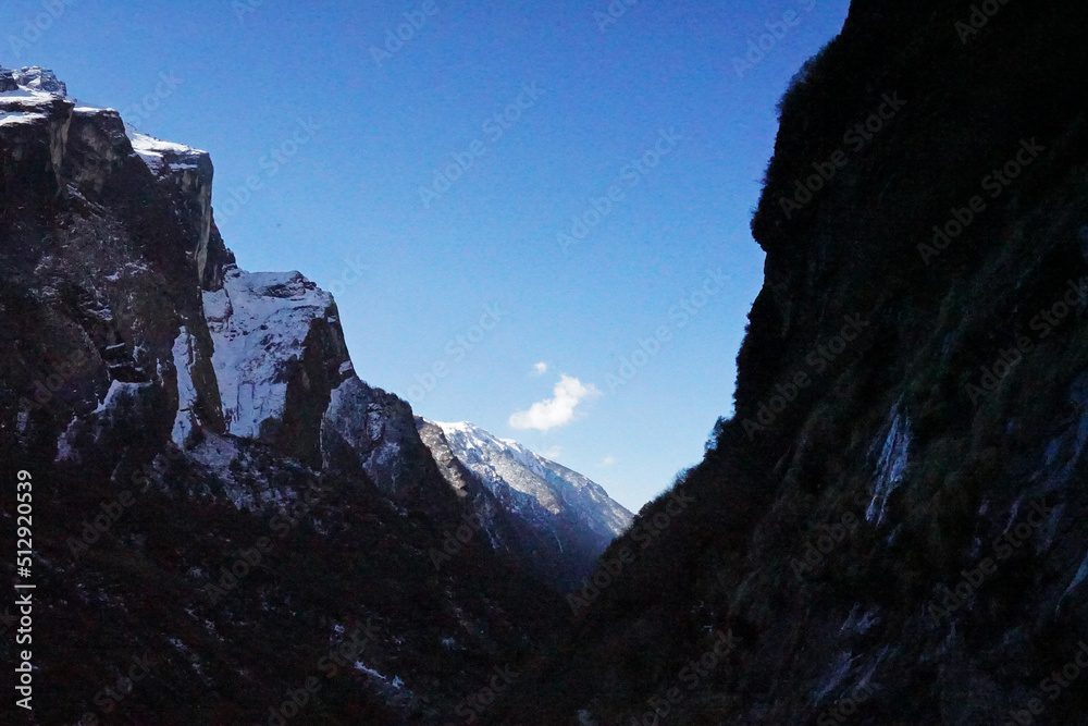 Local Nepali village among natural landscape view of snowcapped mountain cliff and cloudy blue sky- Nepal