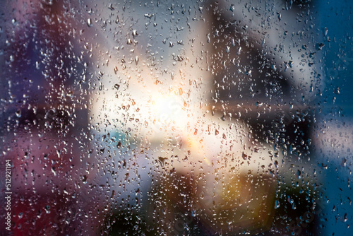 Abstract colorful background with rain drops on window and blurred urban houses