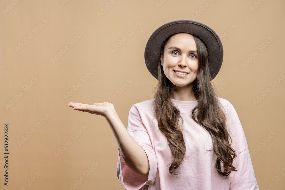 Empty palm with copy space place mock up. Brunette girl with long hair wearing a hat on a beige background