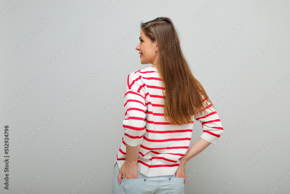Smiling woman with long hair standing back and looking over shoulder, isolated female studio portrait, girl in white sweater with red stripes.. Smiling woman with long hair standing back and looking over shoulder, isolated female studio portrait, girl in white sweater with red stripes..