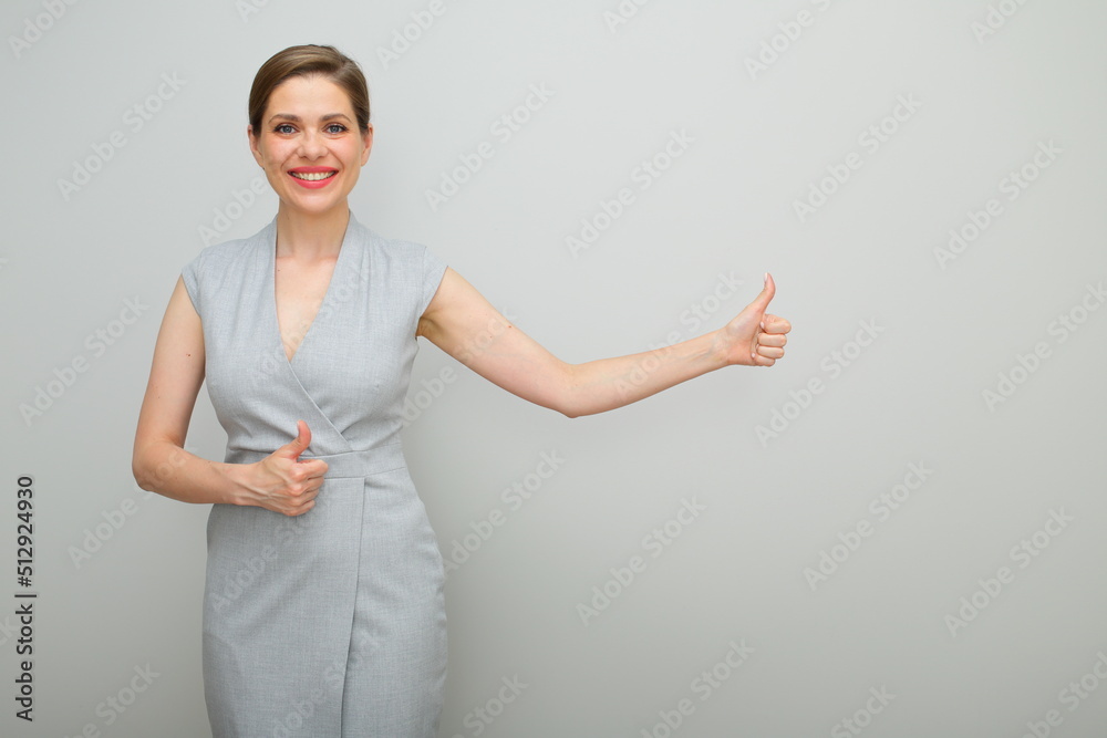 Young business woman with short hairstyle showing thumbs up, isolated portrait, young business lady in gray dress. Young business woman with short hairstyle showing thumbs up, isolated portrait, young business lady in gray dress.