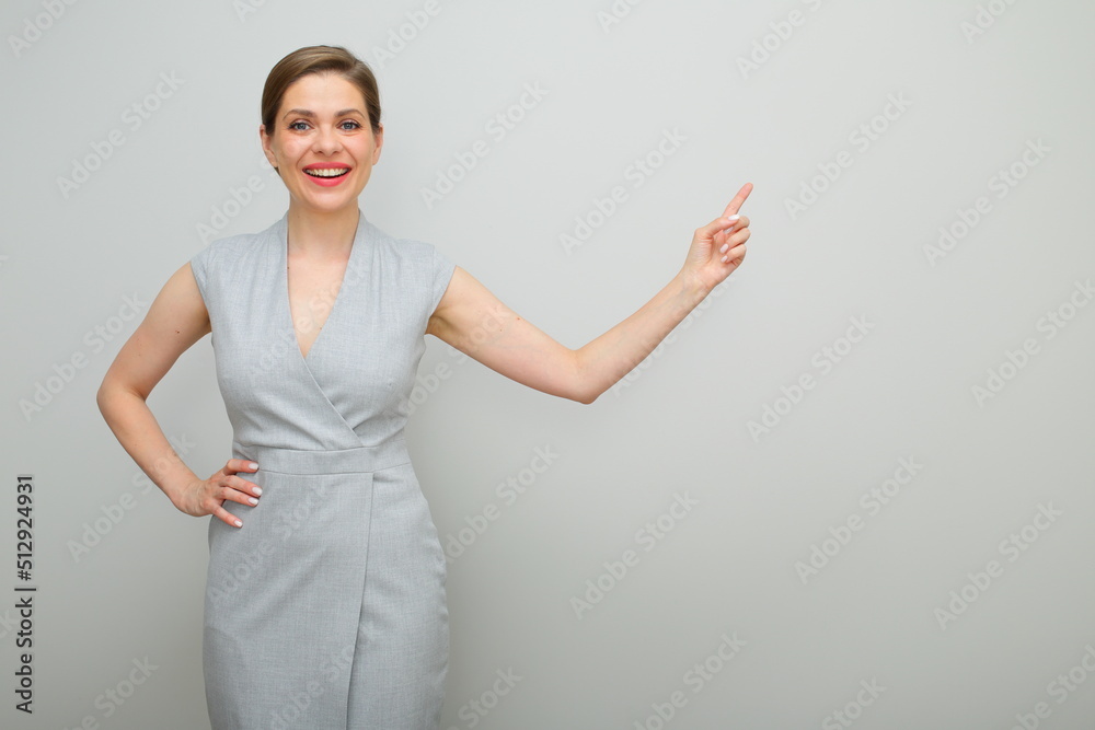 Smiling business woman with short hairstyle pointing finger to copy space, isolated female studio portrait, young business lady in gray dress. Smiling business woman with short hairstyle pointing finger to copy space, isolated female studio portrait, young business lady in gray dress.