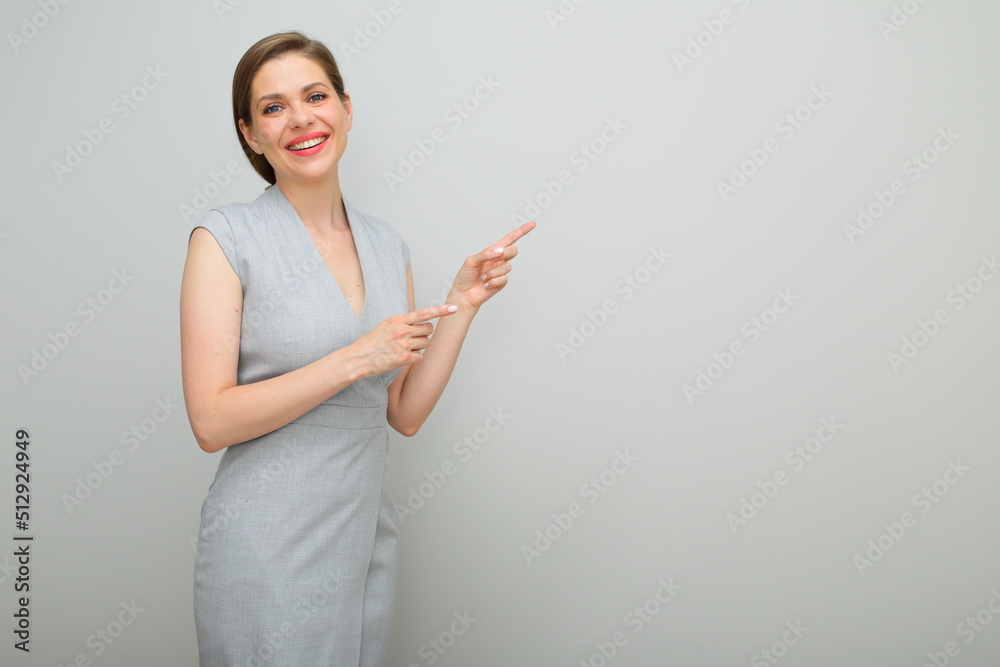 Happy smiling business woman finger pointing to copy space, isolated female portrait, young business lady in gray dress. Happy smiling business woman finger pointing to copy space, isolated female portrait, young business lady in gray dress.