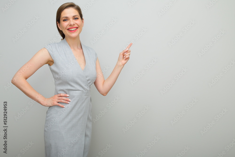 Young business woman with short hairstyle holding hand on hip finger pointing, isolated female studio portrait, young business lady in gray dress. Young business woman with short hairstyle holding hand on hip finger pointing, isolated female studio portrait, young business lady in gray dress.