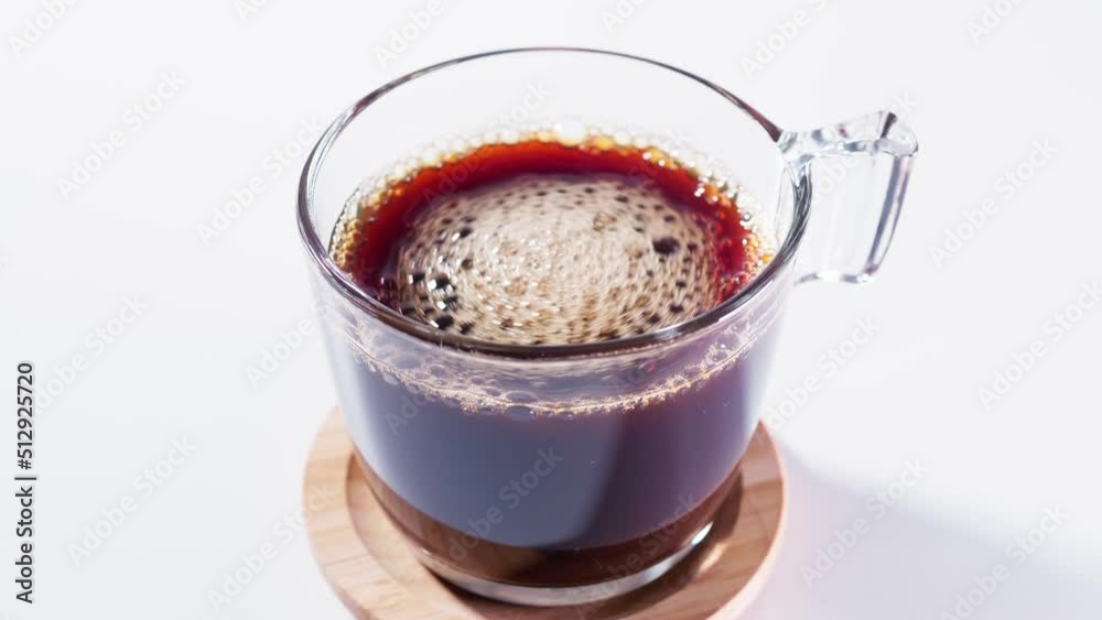 Cup of steaming hot black coffee. Stirring coffee with coffee spoon. Black coffee with white wooden table Cup of steaming hot black coffee. Stirring coffee with coffee spoon. Black coffee with white wooden table