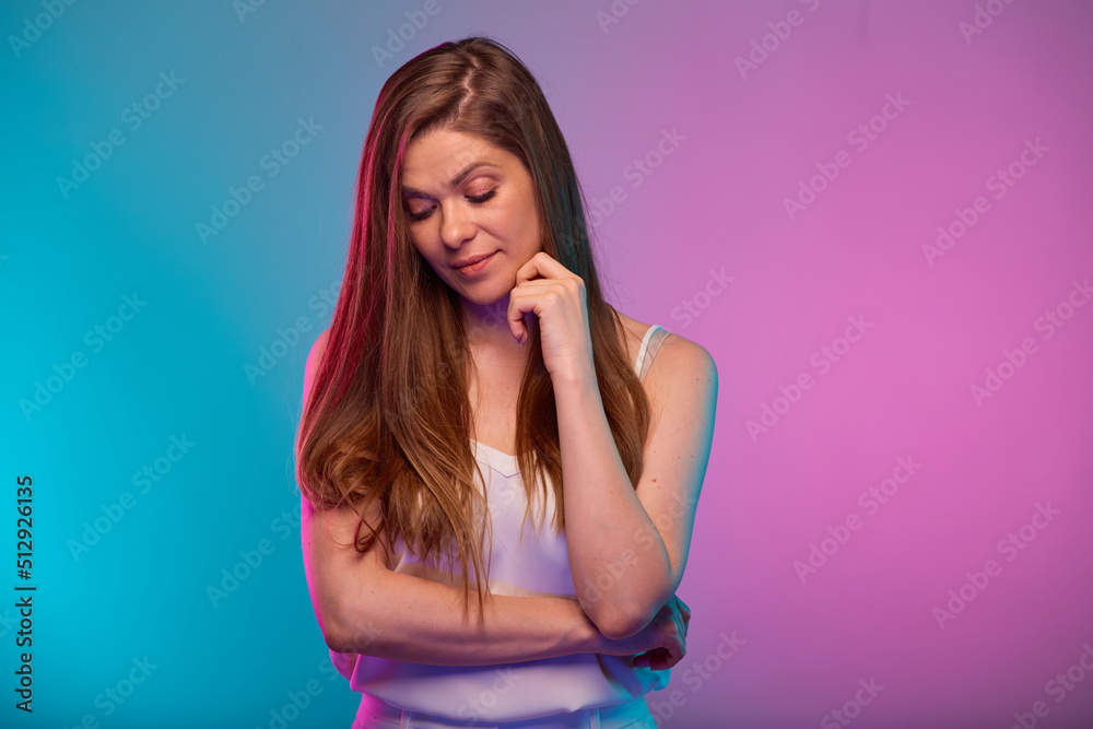 Serious woman looking down, portrait with neon lights colors effect. Female model on neon background Serious woman looking down, portrait with neon lights colors effect. Female model on neon background
