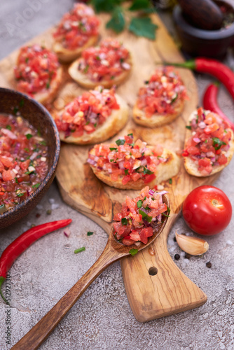 tasty salsa bruschetta snacks at domestic kitchen on wooden cutting board
