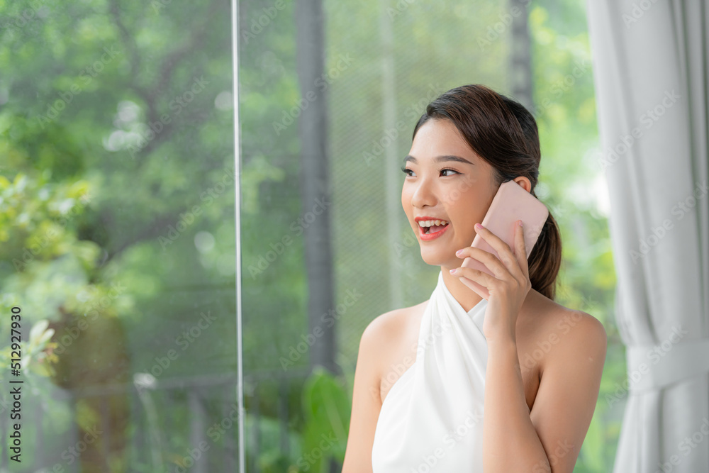 Portrait of beautiful young woman talking on the phone at home.