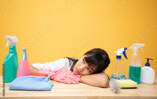 Asian caucasian woman tried and sad while preparing tools with with many cleaning products on table for next week, House clean concept