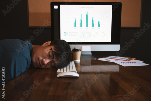 Tired young man in blue shirt sleeping sitting at office desk with laptop computer. Exhausted businessman dozes off after working on keyboards. Night mode