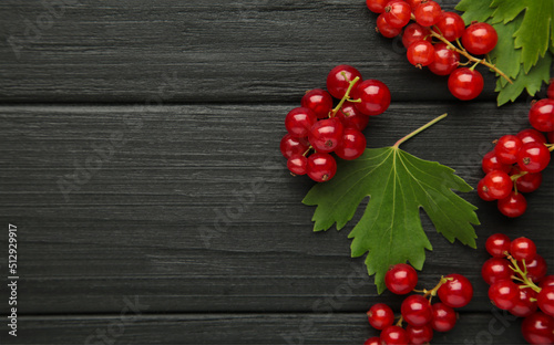 Ripe red currant with green leaves on dark wooden background. Top view.