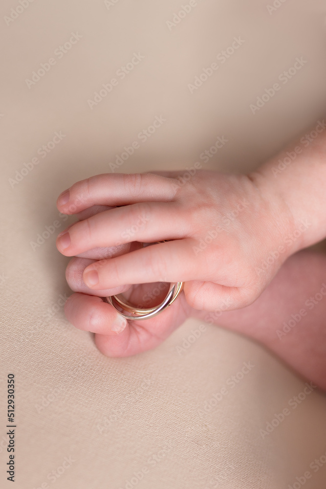 Fototapeta premium hand of a newborn with wedding rings of parents. small pens. hands on a white background. ring in a child's hand