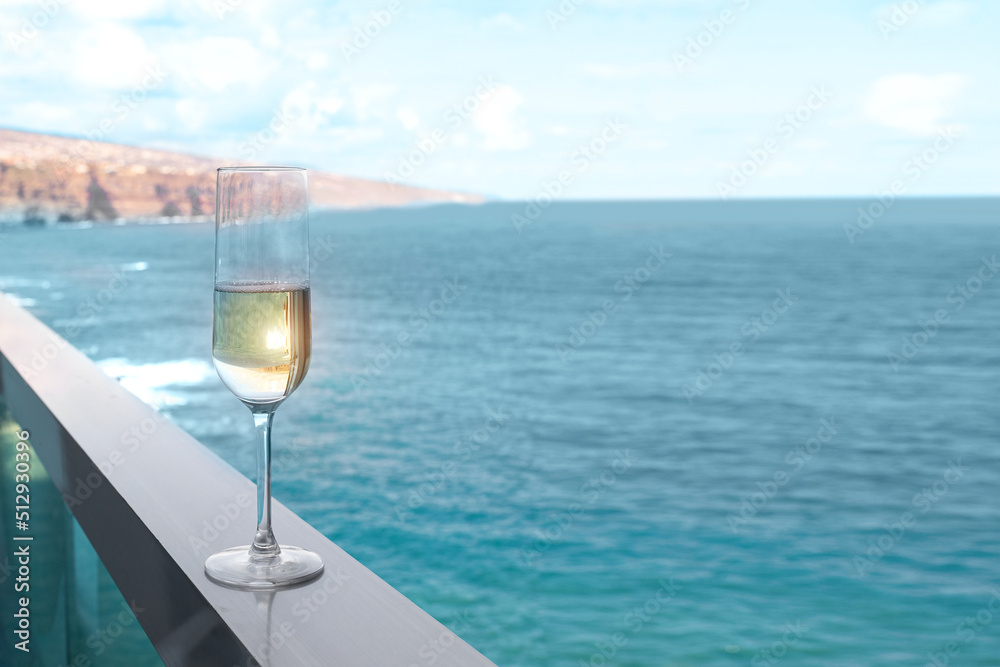 Concept for luxury vacation. One champagne glass on hotel balcony with beautiful ocean view in tropical country.