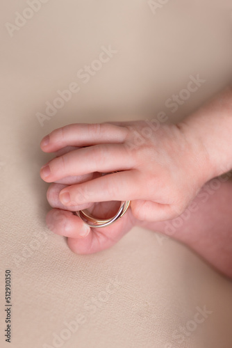 hand of a newborn with wedding rings of parents. small pens. hands on a white background. ring in a child's hand
