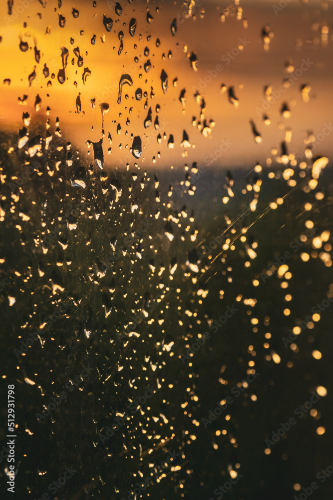 Outside the window, an evening street in Ivano-Frankivsk. Water drops on a window glass after the rain. The sun and sky with clouds on background