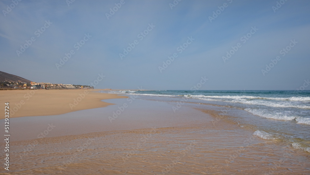 Empty and tranquil beach with golden sand and clear blue waters known locally as Playa de Costa Calma, stretching along the south-eastern coast of the island of Fuerteventura, Canary Islands, Spain Empty and tranquil beach with golden sand and clear blue waters known locally as Playa de Costa Calma, stretching along the south-eastern coast of the island of Fuerteventura, Canary Islands, Spain
