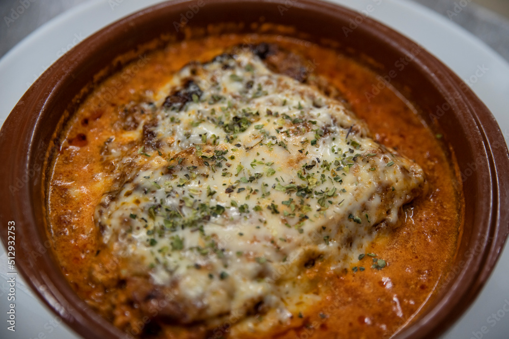 Homemade lasagna baked in a terracotta round pot, individual portion of the traditional Italian dish made of layers of lasagne pasta, delicious ragu sauce, rich bechamel gratin with dried herbs on top Homemade lasagna baked in a terracotta round pot, individual portion of the traditional Italian dish made of layers of lasagne pasta, delicious ragu sauce, rich bechamel gratin with dried herbs on top