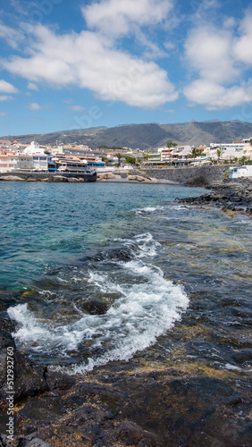 Views of the small picturesque village from the ocean level upwards towards the residential buildings, restaurants and promenade, La Caleta, Costa Adeje, Tenerife, Canary Islands, Spain