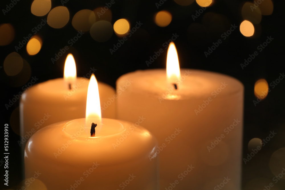 Wax candles burning on black background with blurred lights, closeup. Bokeh effect Wax candles burning on black background with blurred lights, closeup. Bokeh effect