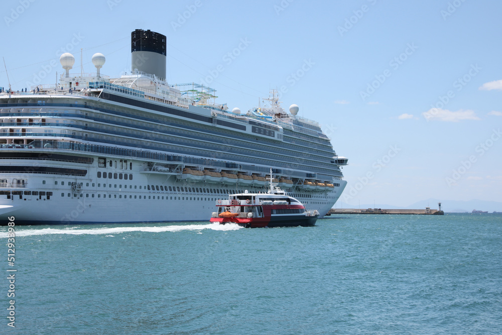 Modern cruise ship and boat in sea on sunny day