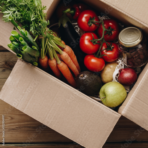 Food selection in paper box: fruit, vegetable, herbs, legumes, cereals, leaf vegetable on wooden background.